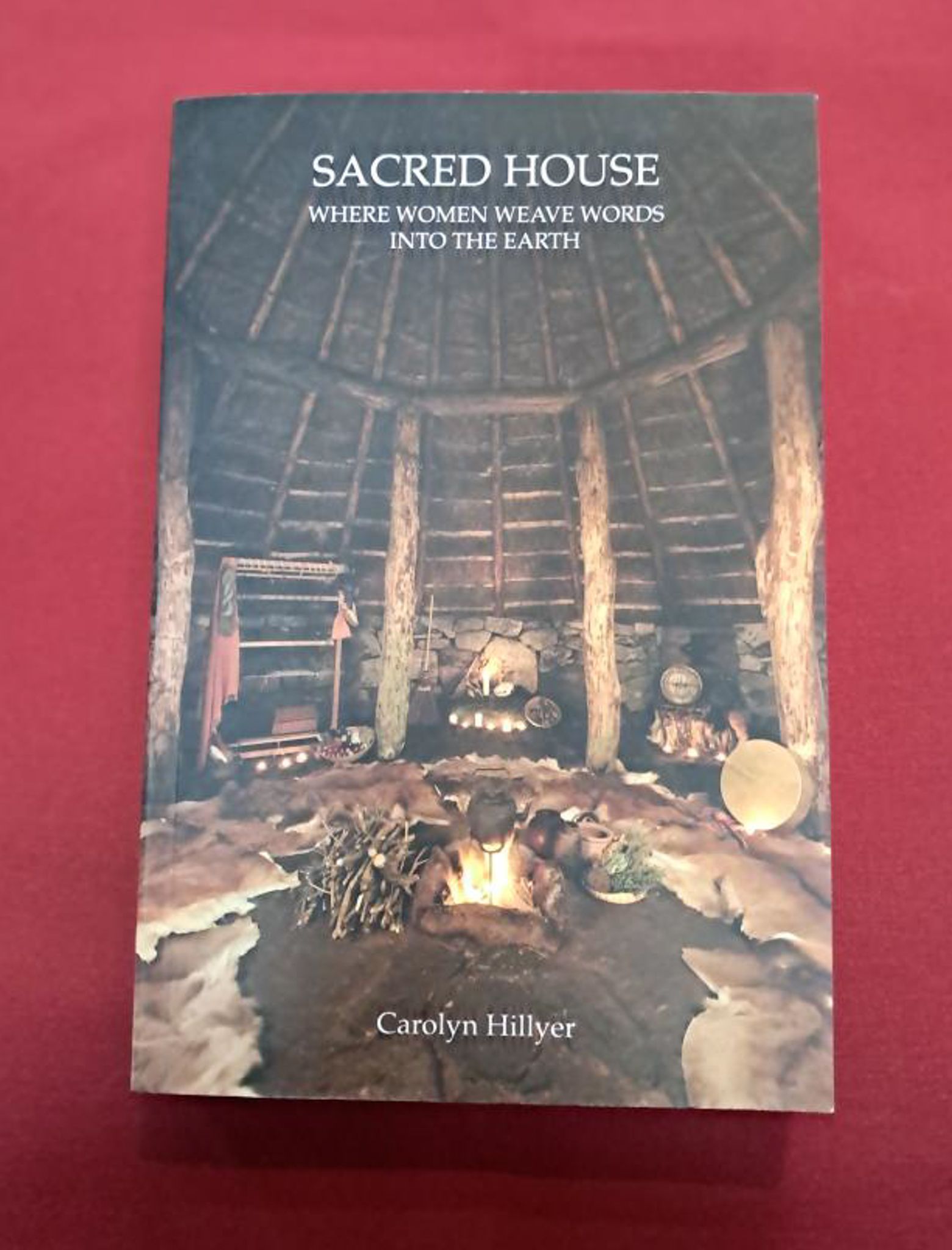 Sacred House. A photograph of a hearth around an open fire, with sticks, pots and trinkets